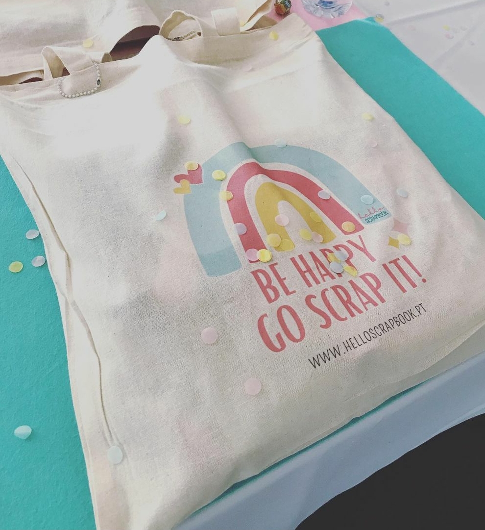 Mala de tecido bege com desenho de arco-íris e texto motivacional em tons pastel