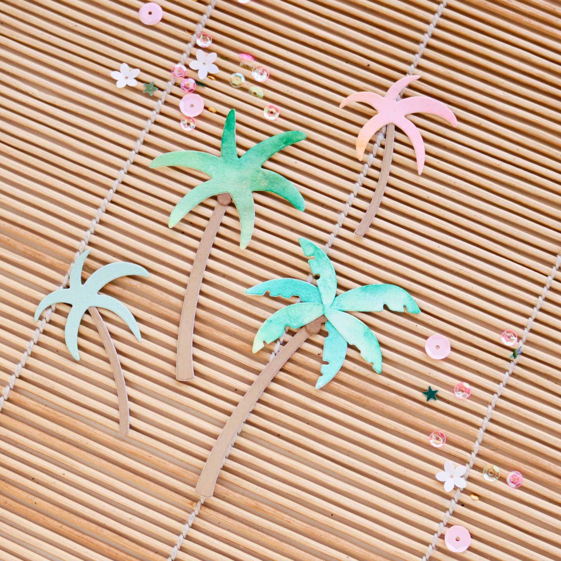 Colares com pingentes de palmeiras coloridas em superfície de ripas de madeira