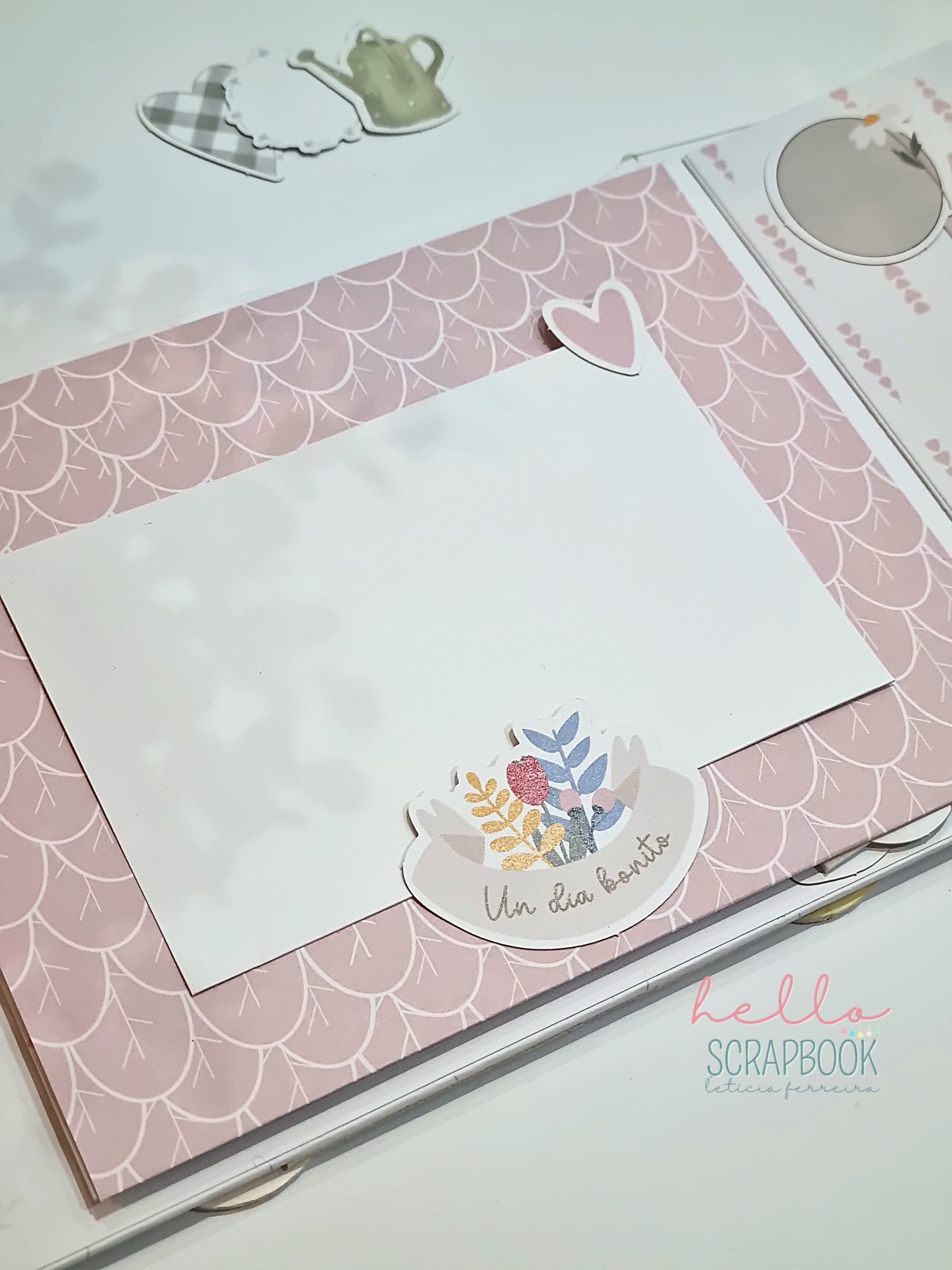Álbum de scrapbook decorado com moldura rosa e cartão branco para foto com adesivo floral e texto em espanhol