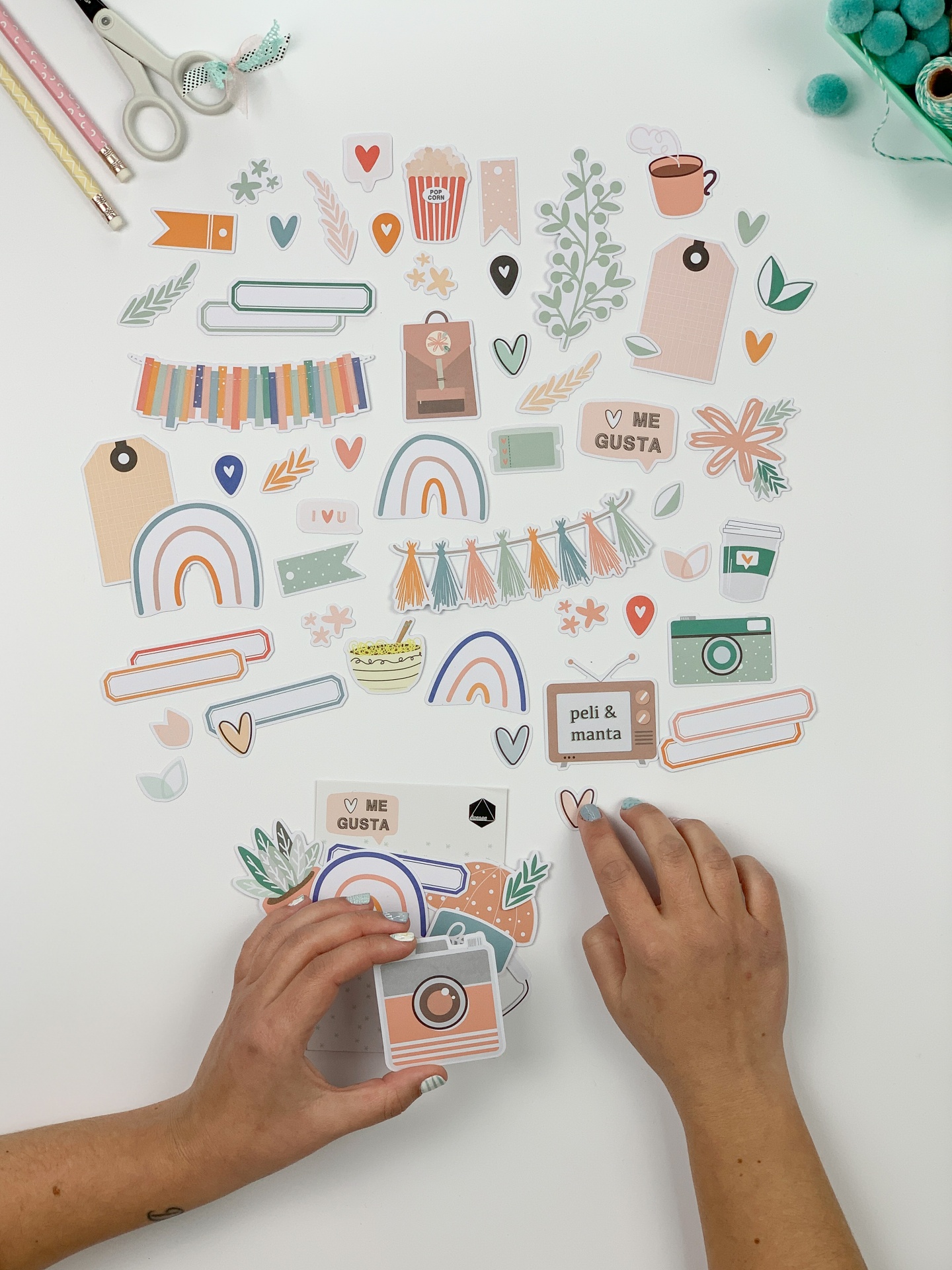 Cartões decorativos coloridos com mãos a organizar sobre mesa branca