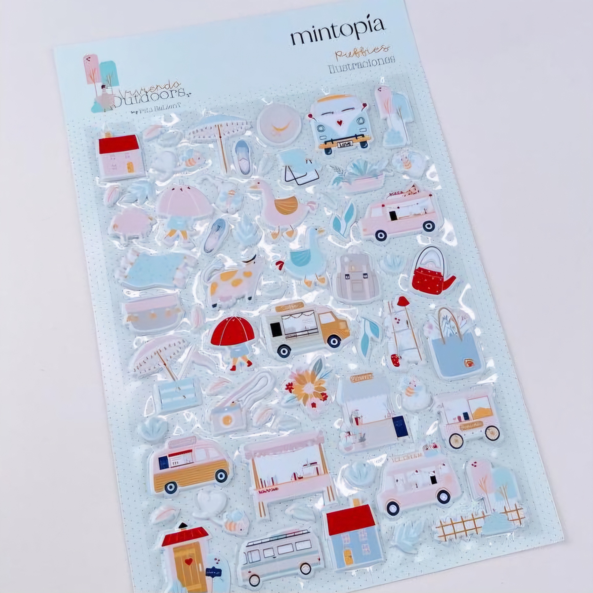 Folha de autocolantes variados coloridos com desenhos de objetos e veículos sobre fundo azul claro