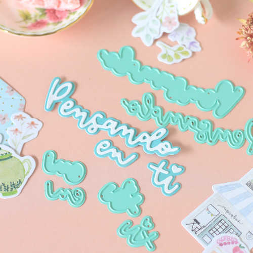 Moldes de corte azuis com frases em português sobre superfície rosa e recortes decorativos