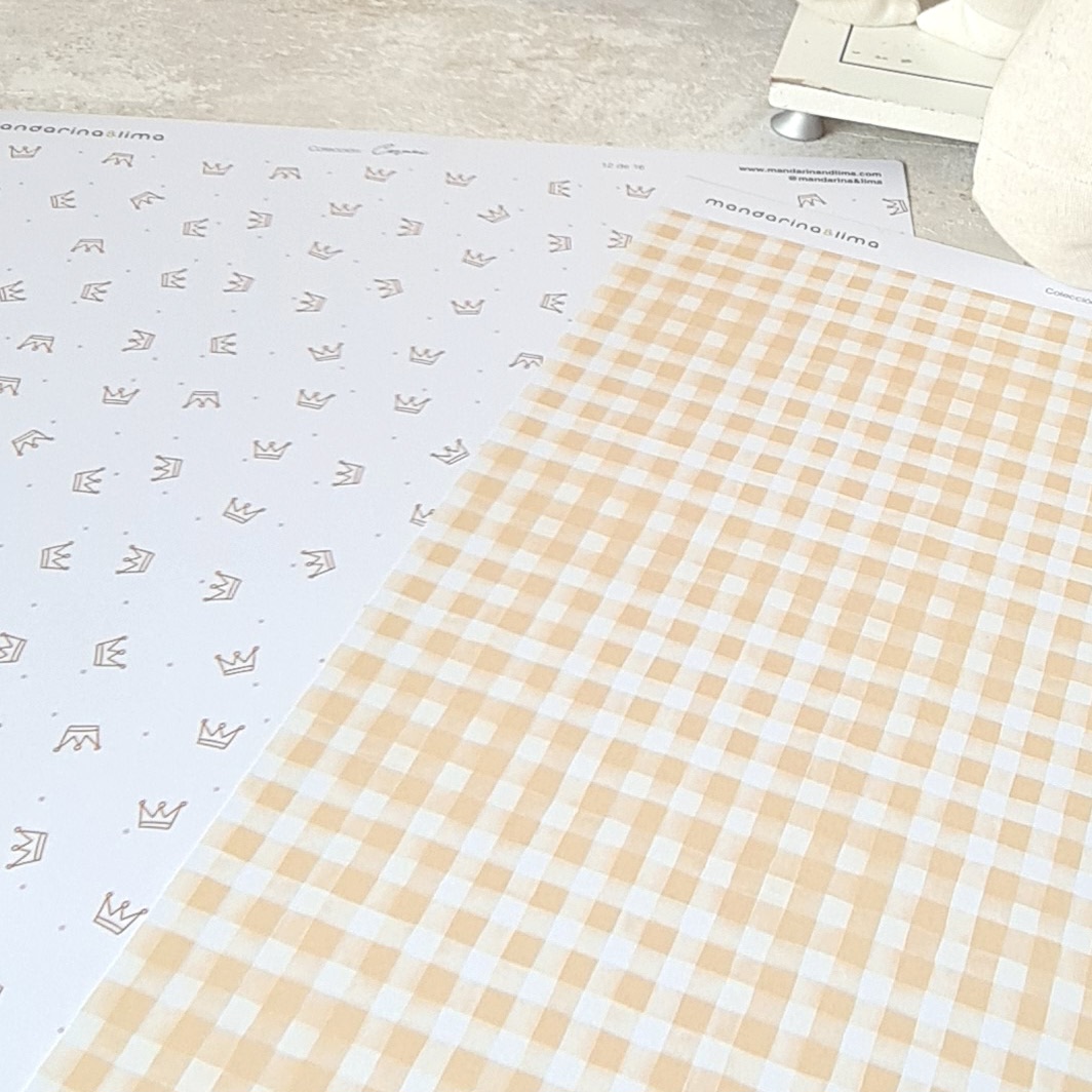 Tecidos com padrões de coroas e quadriculado bege sobre superfície clara