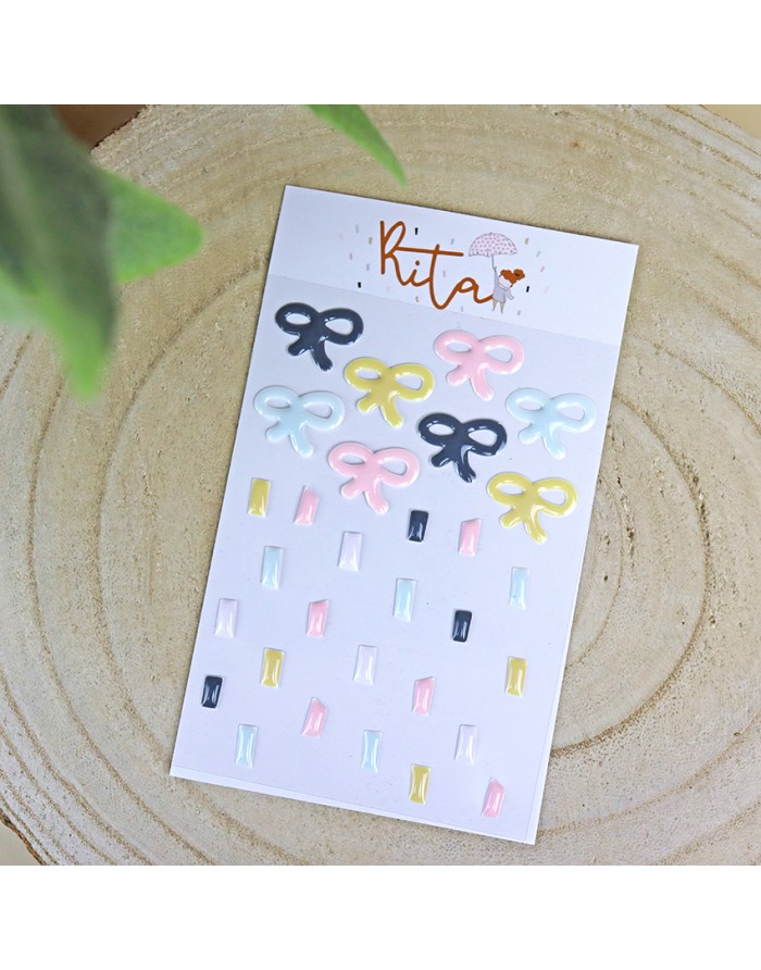 Cartão com adesivos de laços e retângulos coloridos sobre madeira clara