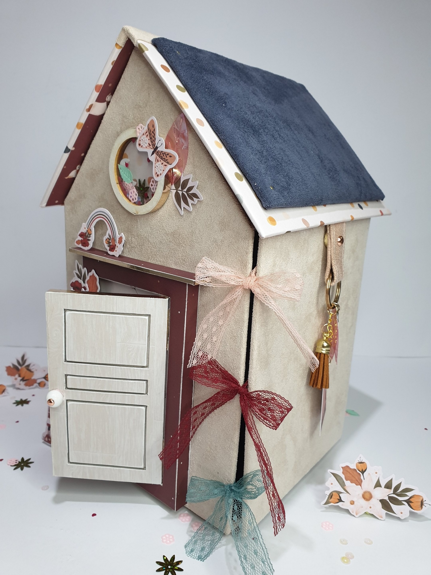Casa decorativa em tecido e madeira com porta aberta e ornamentos coloridos