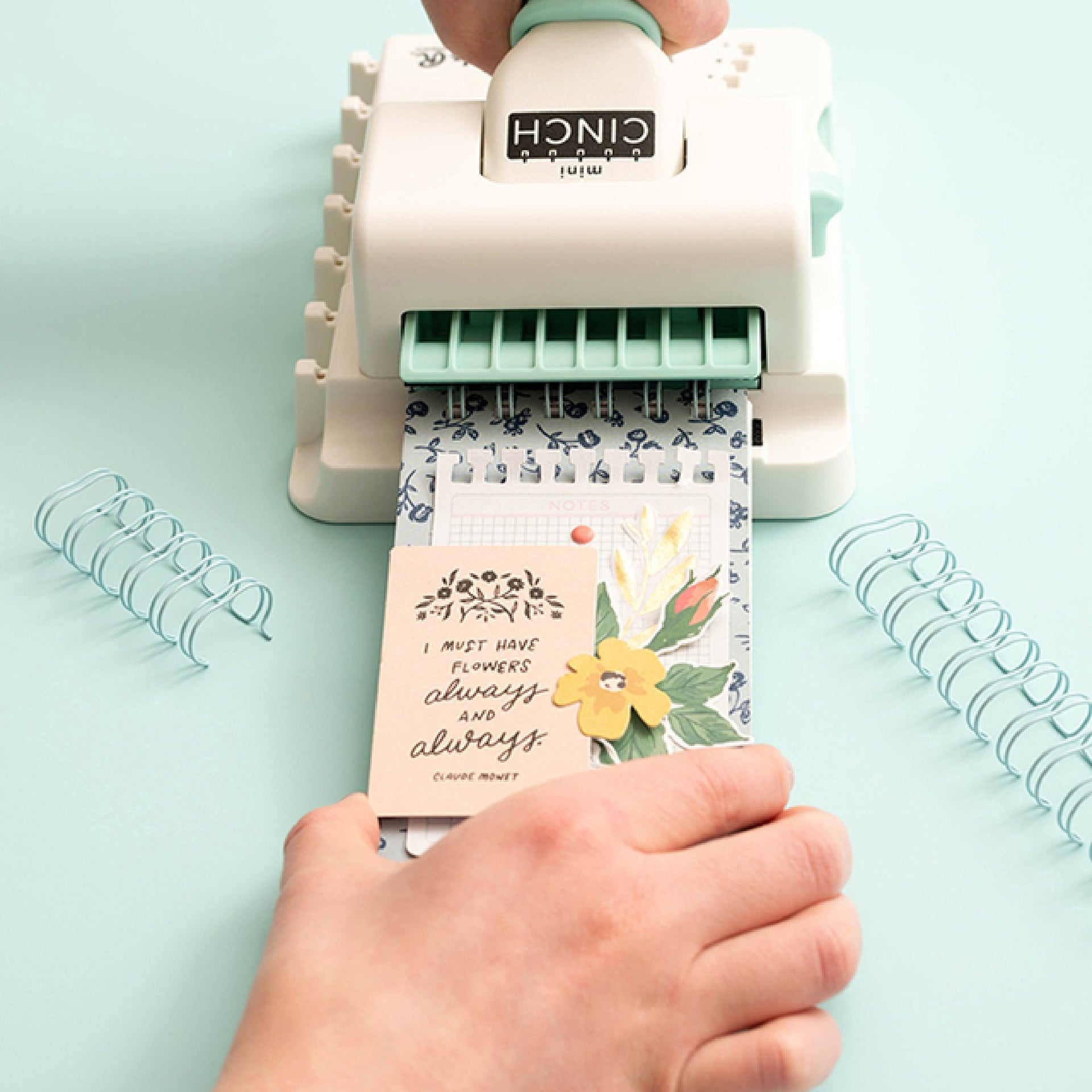 Máquina de encadernação branca e verde com folhas perfuradas e mensagem decorativa