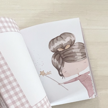 Caderno aberto com capa xadrez rosa e branca e ilustração de menina com varinha de estrela