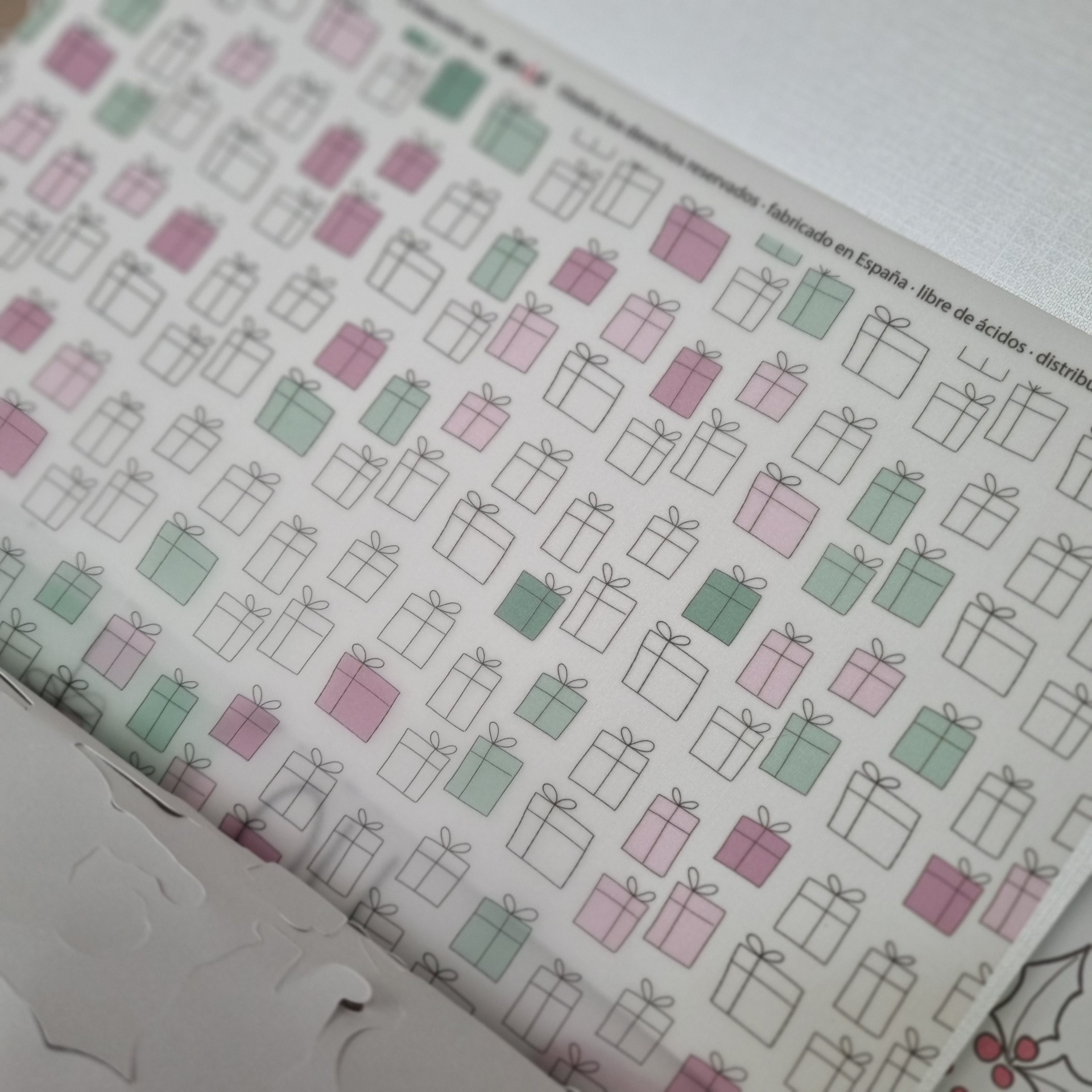 Folha de papel com padrão de presentes coloridos e texto em espanhol no topo