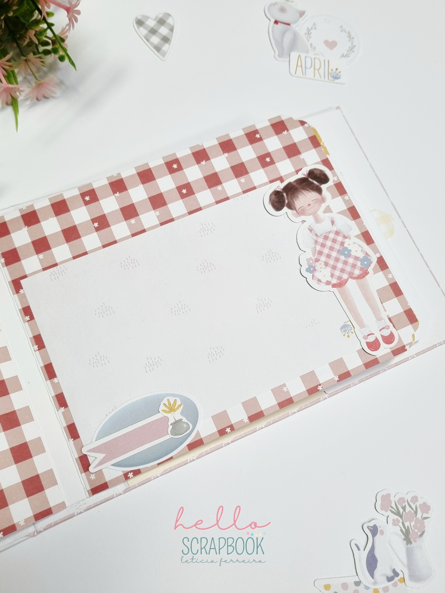 Caderno scrapbook aberto com padrão xadrez vermelho e branco e ilustrações decorativas