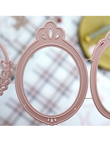 Moldura decorativa redonda rosa com detalhes recortados sobre superfície xadrez