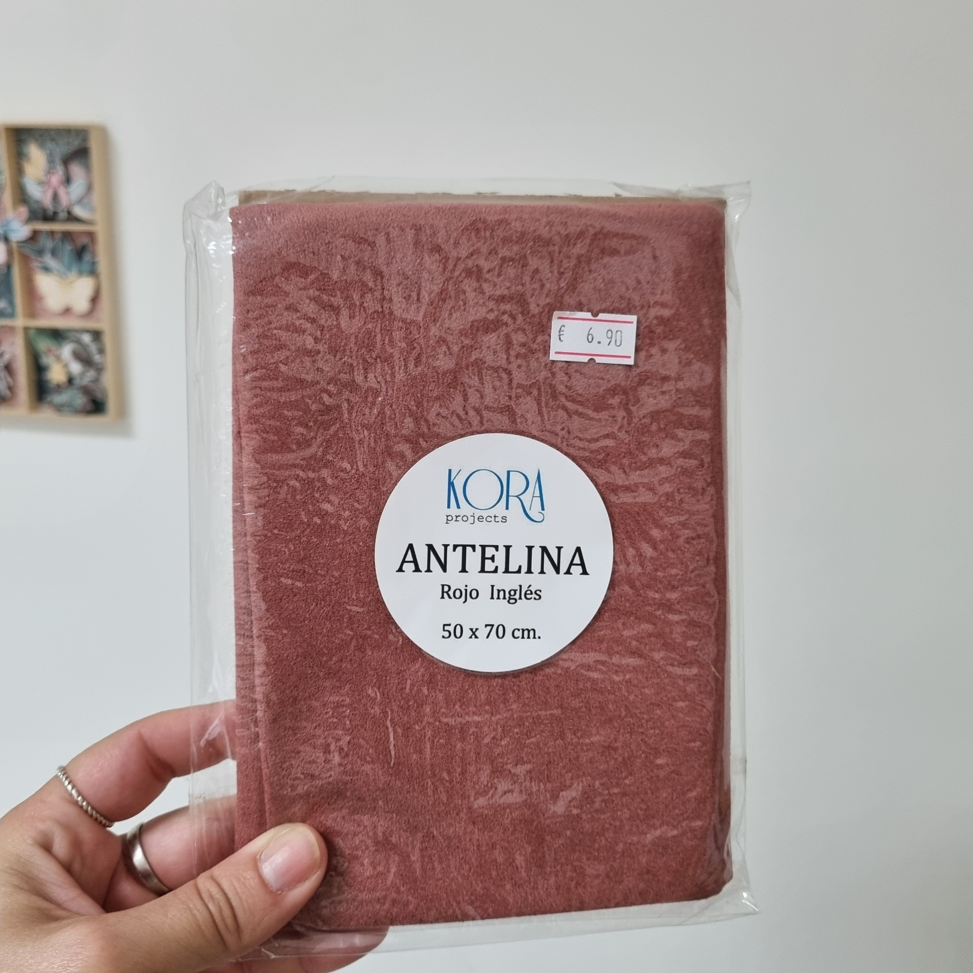 Toalhete vermelha microfibra embalada com etiquetas visíveis e mão a segurá-la