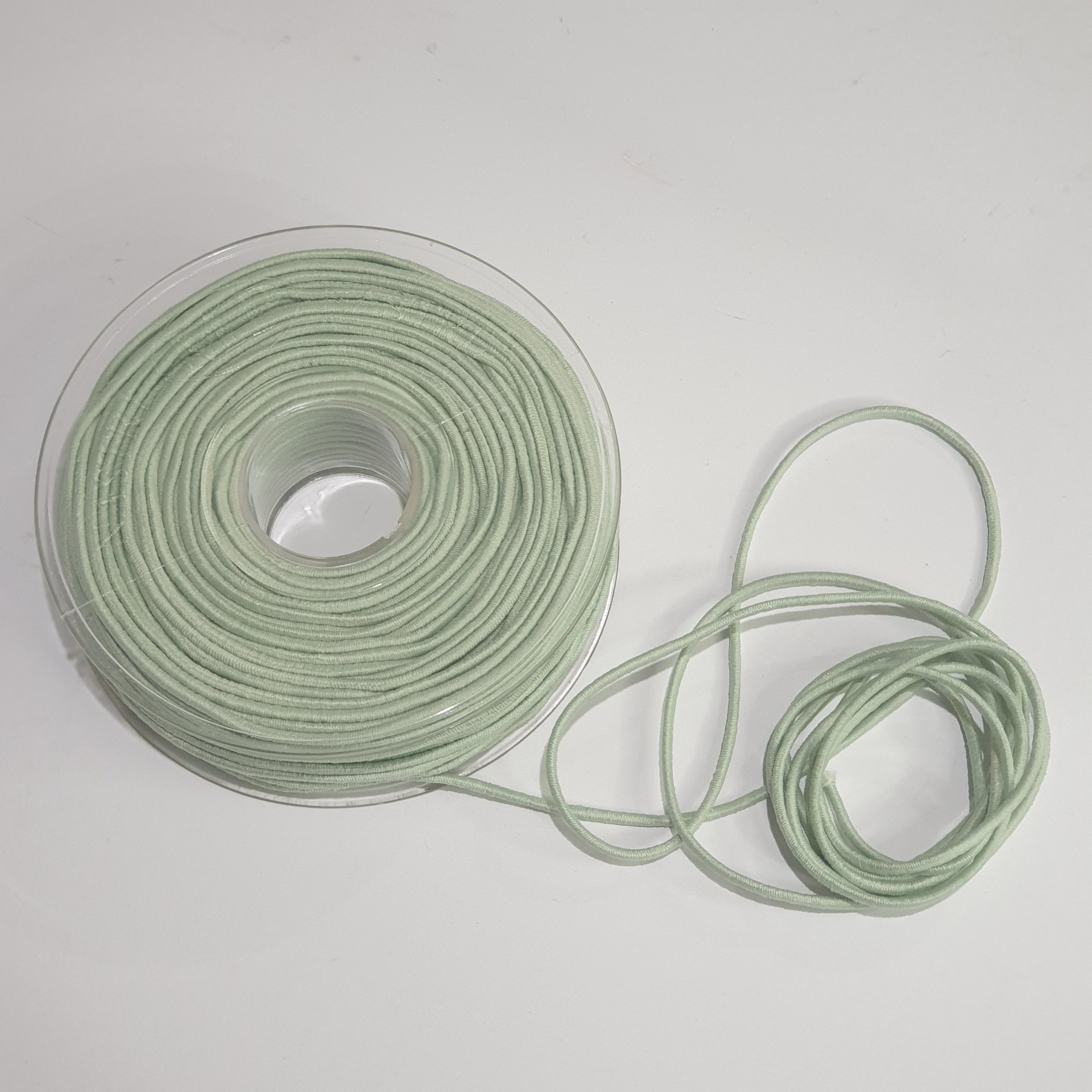 Rolo de cordão verde claro em carretel transparente