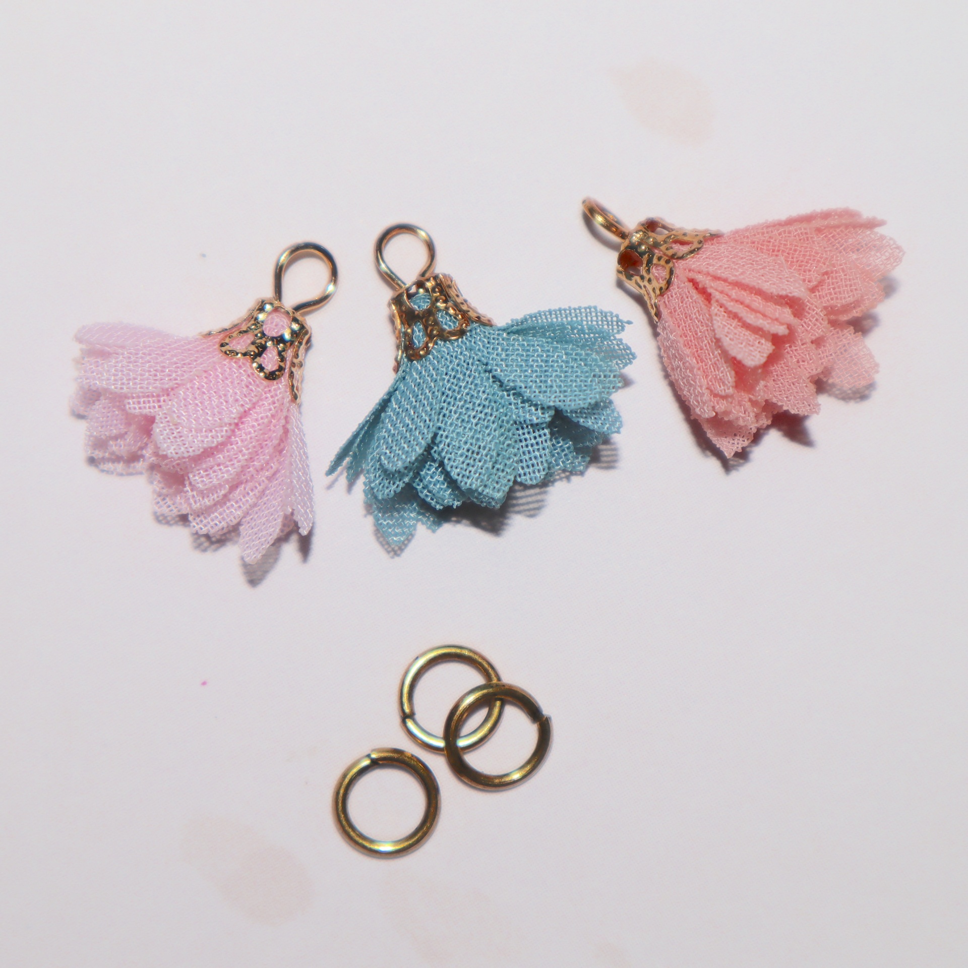Três pendentes florais de tecido em rosa claro, azul e rosa escuro com argolas metálicas douradas