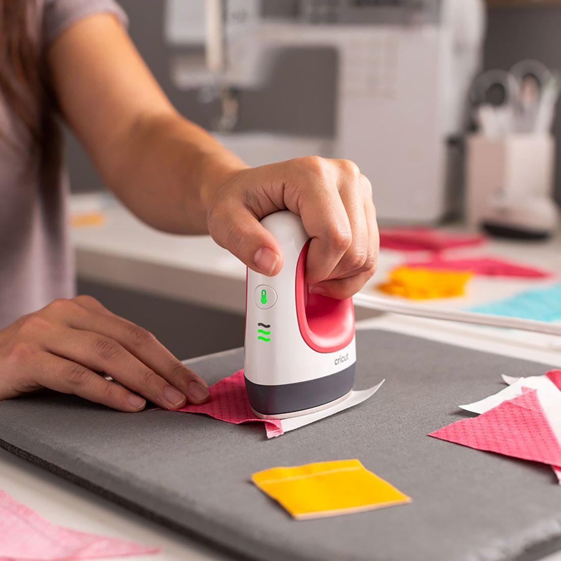 Ferro elétrico branco e rosa sobre tecido cor-de-rosa numa mesa de costura