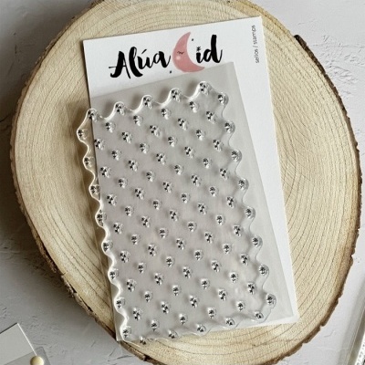 Placa transparente de silicone para carimbos com pontilhado, colocada em embalagem branca com logótipo e sobre base de madeira redonda.