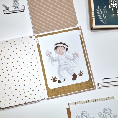 Folhas decorativas para scrapbook com desenhos de criança vestida de múmia, padrões de pontos castanhos e riscas finas.
