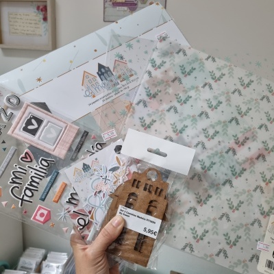 Materiais para scrapbooking com papel floral, adesivos e madeira em embalagem transparente