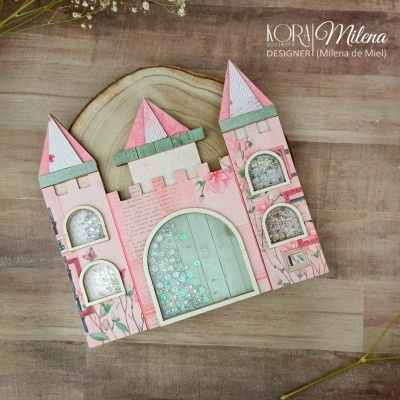 Castelo decorativo rosa com janelas transparentes e lantejoulas azuis sobre fundo de madeira clara