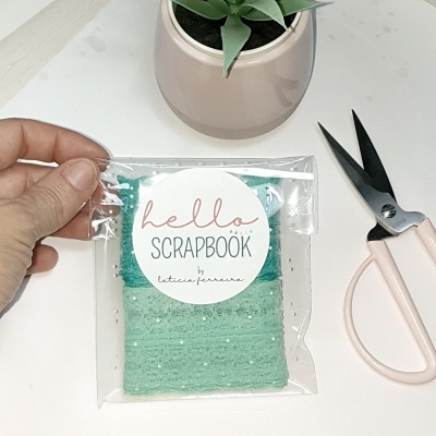 Fita decorativa verde com pontos brancos em embalagem, mão, tesoura rosa e vaso com planta