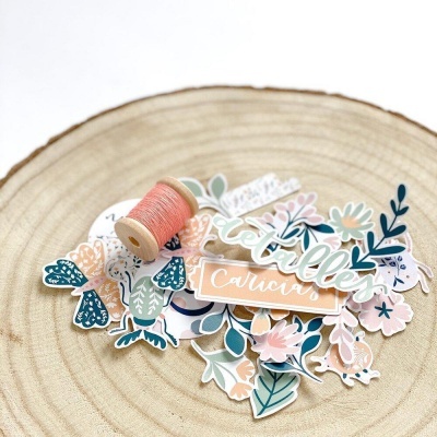 Figuras e etiquetas decorativas florais em papel com linha cor de salmão sobre madeira clara