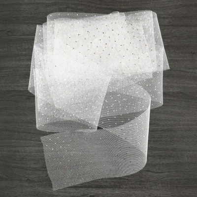 Lenço branco translúcido com pontos dourados sobre madeira escura