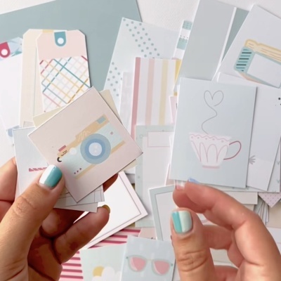 Pequenos cartões e etiquetas de papel coloridos em mãos com unhas verdes