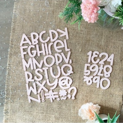 Letras e números recortados cor de rosa sobre tecido juta e flores