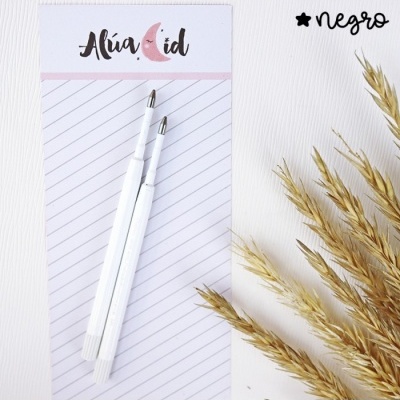 Duas canetas brancas sobre bloco de notas e ramos secos ao lado