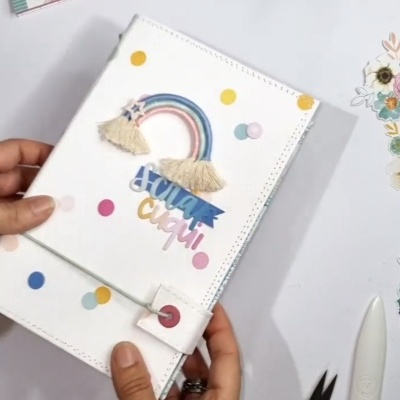 Capa de caderno branco com arco-íris e texto colorido