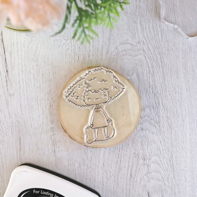 Carimbo de borracha com desenho de personagem sobre base de madeira redonda