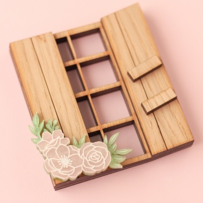 Porta de madeira decorativa com janela e flores estilizadas em fundo rosa