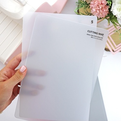 Bases de corte transparentes em plástico fosco com texto preto, seguradas por mão feminina