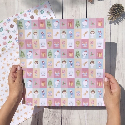 Folha de papel de embrulho natalício com padrão quadriculado colorido segurada por duas mãos