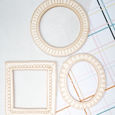 Três molduras decorativas de madeira clara com desenhos gravados em parede branca