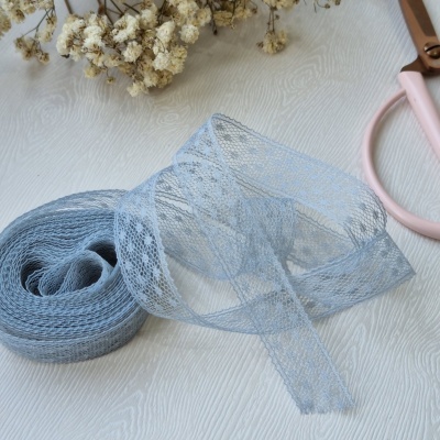 Fita de renda azul claro com padrão delicado junto a flores secas e tesoura rosa