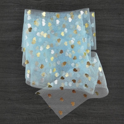 Tecido de rede azul claro com pontos dourados, prateados e brancos sobre superfície escura