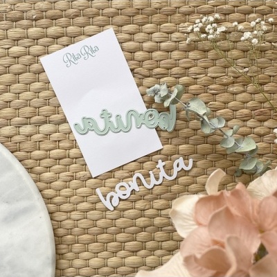 Palavras recortadas 'natural' e 'bonita' sobre cartão e tecido com flores secas