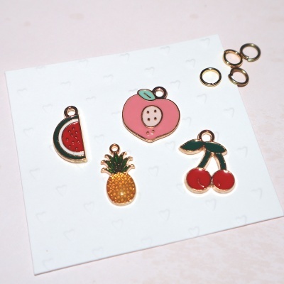 Pendentes coloridos em forma de frutas sobre cartão branco