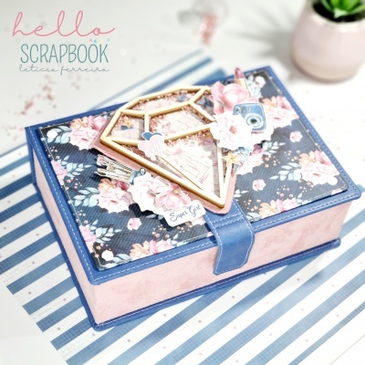 Estojo de scrapbook decorado com padrão floral e apliques de papel sobre superfície riscada azul e branca