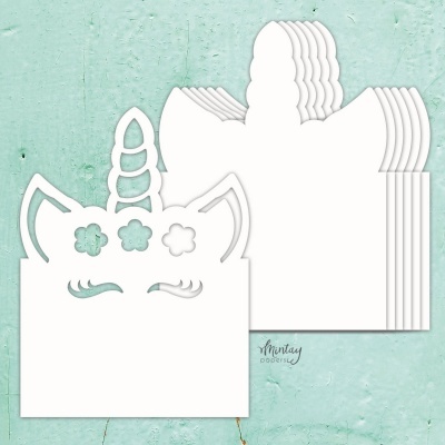 Moldes de papel branco em forma de rosto de unicórnio sobre superfície verde-azulada