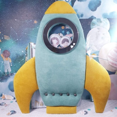 Brinquedo foguete azul-petróleo e amarelo com janela circular