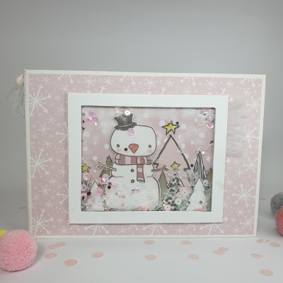 Quadro decorativo com boneco de neve e árvores em fundo rosa com flocos de neve