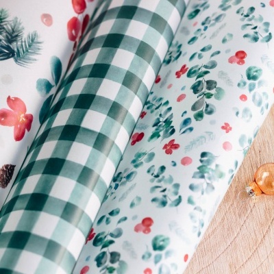 Rolos de papel de embrulho com padrões florais e xadrez sobre base de madeira