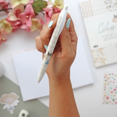 Caneta branca com padrão de linhas azuis e ilustração de cão em mão com unhas azuis claras