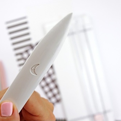 caneta branca com símbolo de lua e fundo geométrico desfocado