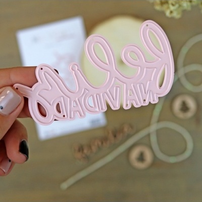 Recorte rosa acrílico com texto invertido 'Feliz Aniversário' segurado pela mão