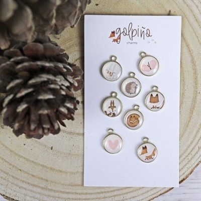 Conjunto de pendentes redondos com ilustrações de animais e corações em cartão branco sobre madeira clara