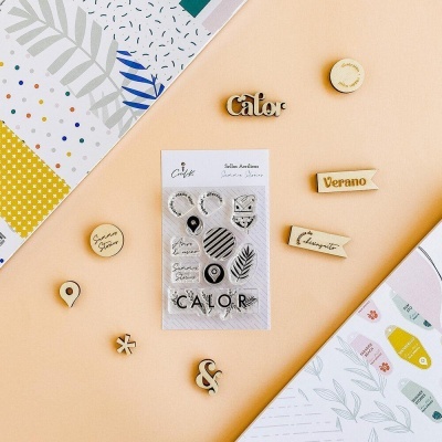 Selos decorativos e acessórios de madeira com palavras em espanhol sobre fundo colorido e com papéis de padrões variados