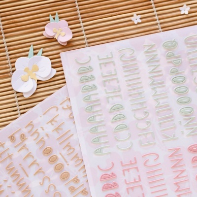 Autocolantes de letras coloridas e autocolantes de flores orquídeas numa esteira de bambu