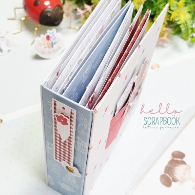 Álbum scrapbook decorado com padrões florais e xadrez ao lado de figura de joaninha